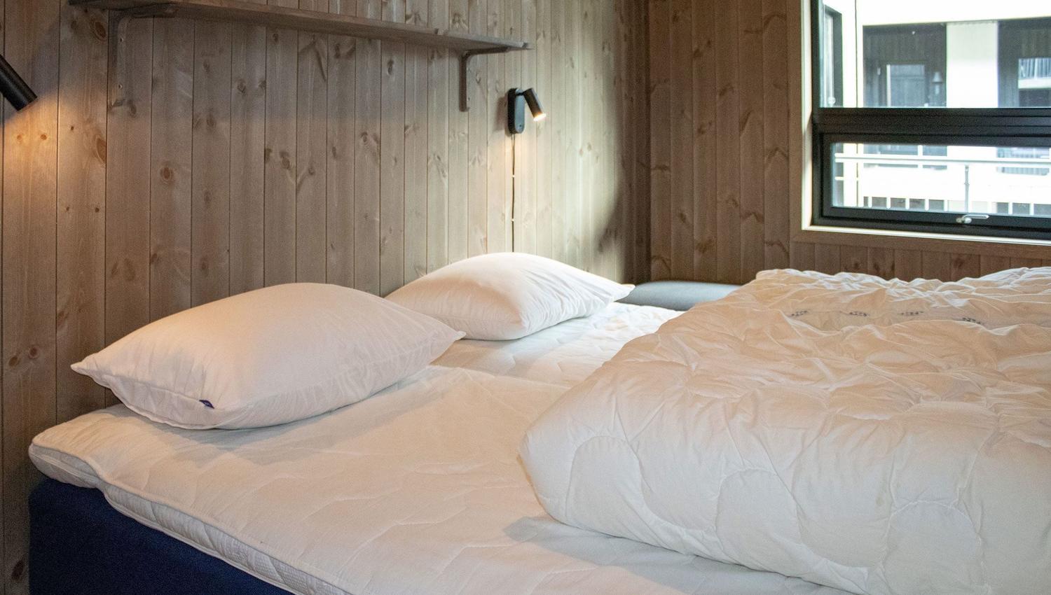 Ein Bett mit Kissen und einer Lampe in einem Zimmer.