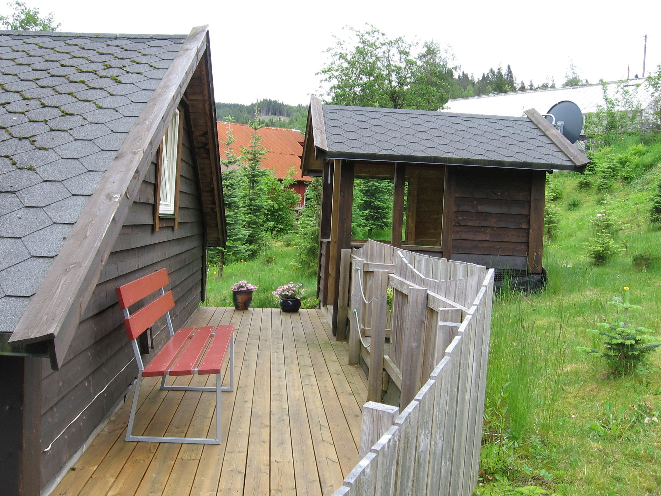 Cozy outdoor area with wooden deck, bench and flowers at Vågen Rom og Hytteutleige in Hardanger.