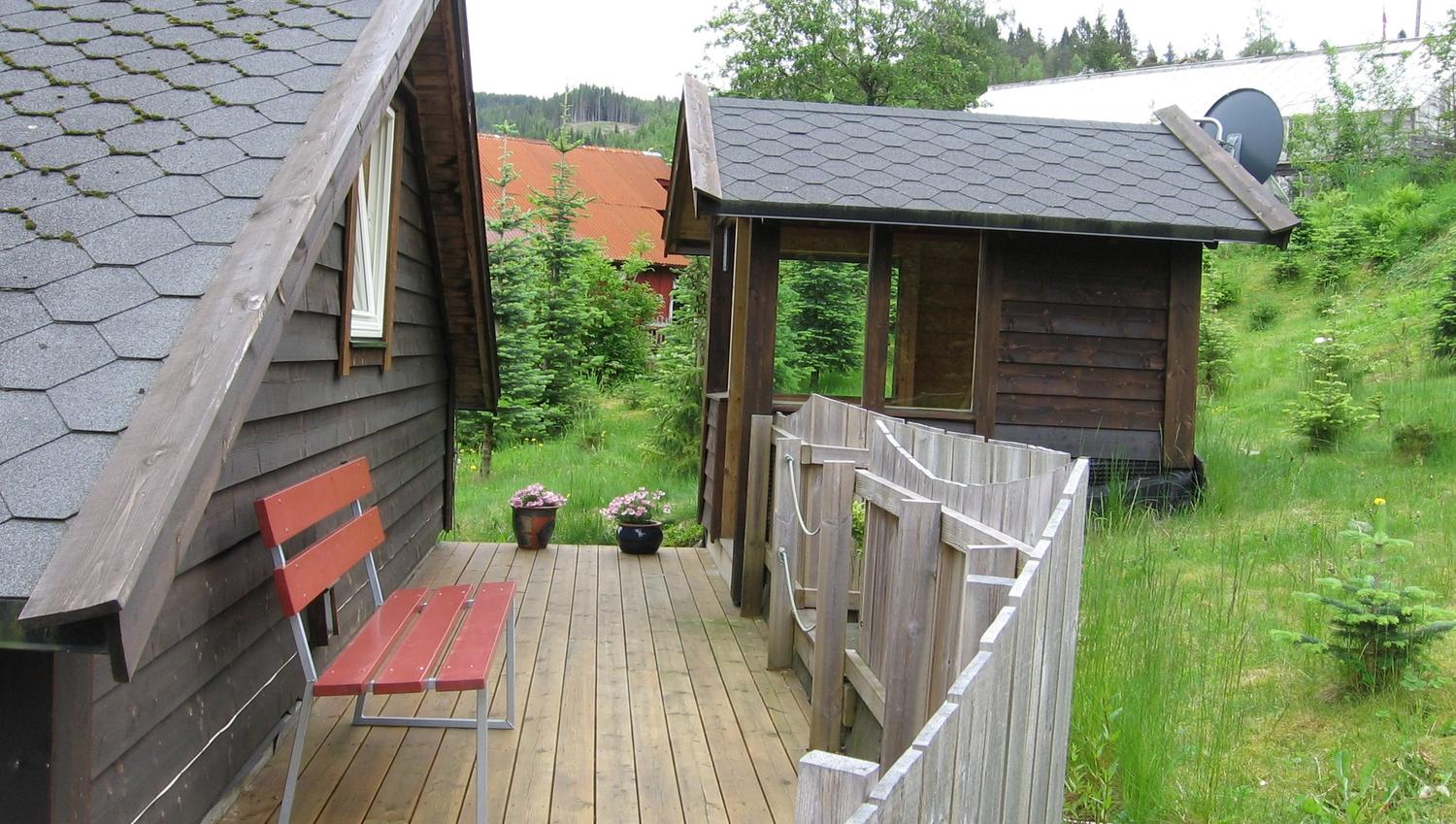 Cozy outdoor area with wooden deck, bench and flowers at Vågen Rom og Hytteutleige in Hardanger.