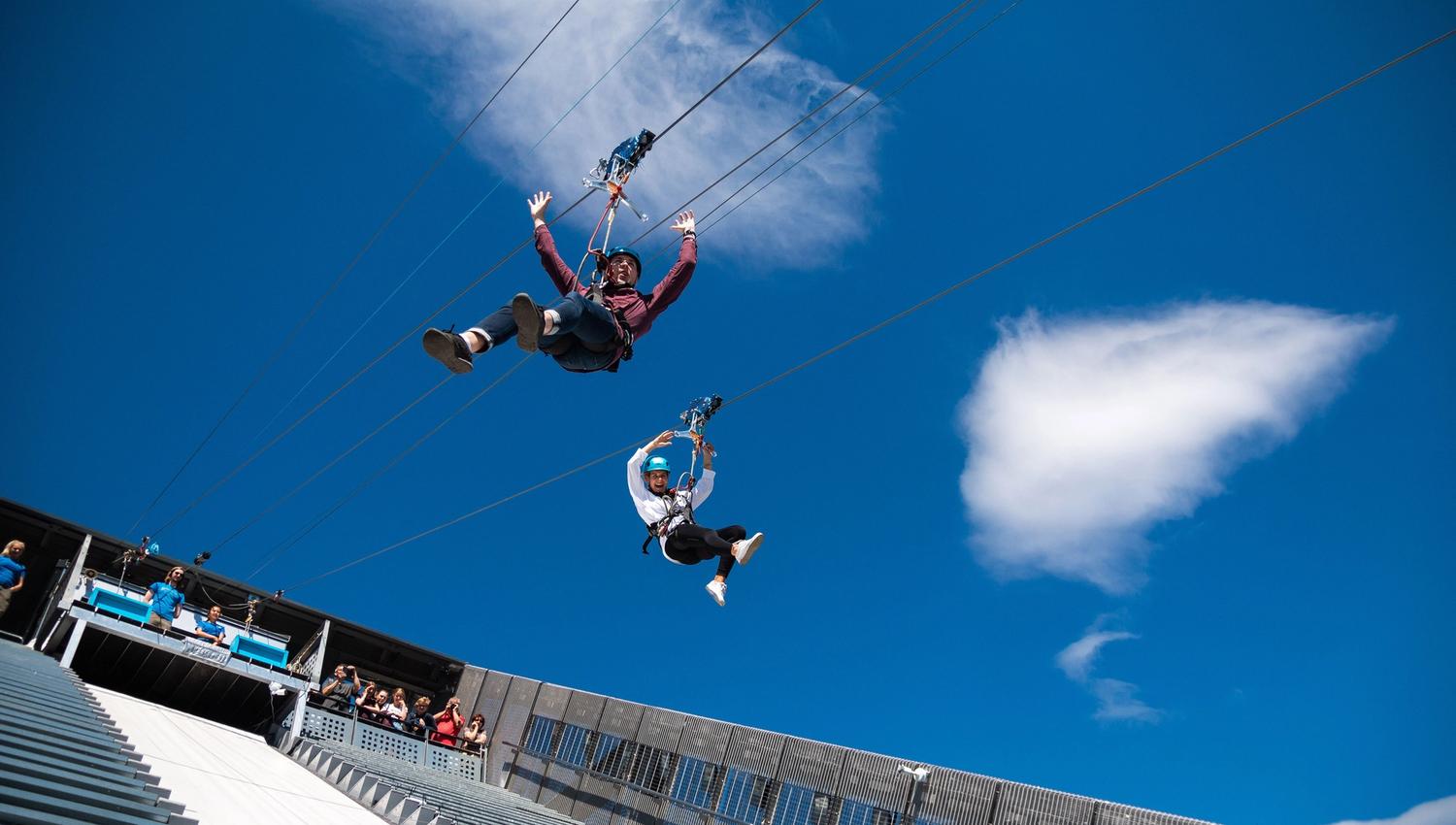 Two people ziplining down Holmenkollen Ski Jump.