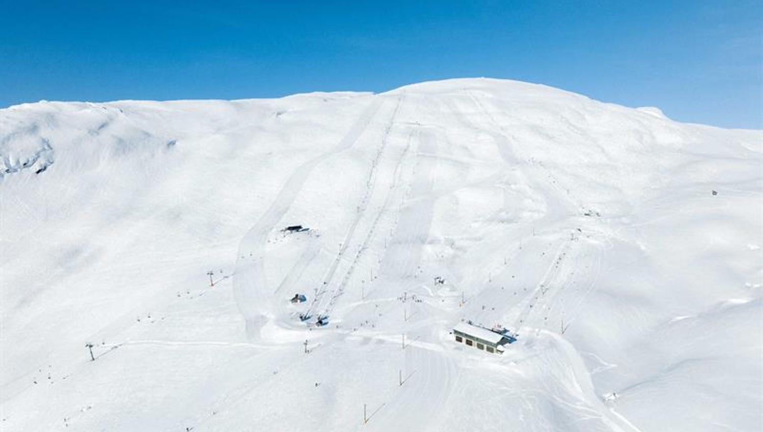 Präparierte Skipisten und Lifte im Røldal Skigebiet unter blauem Himmel und funkelndem Schnee.