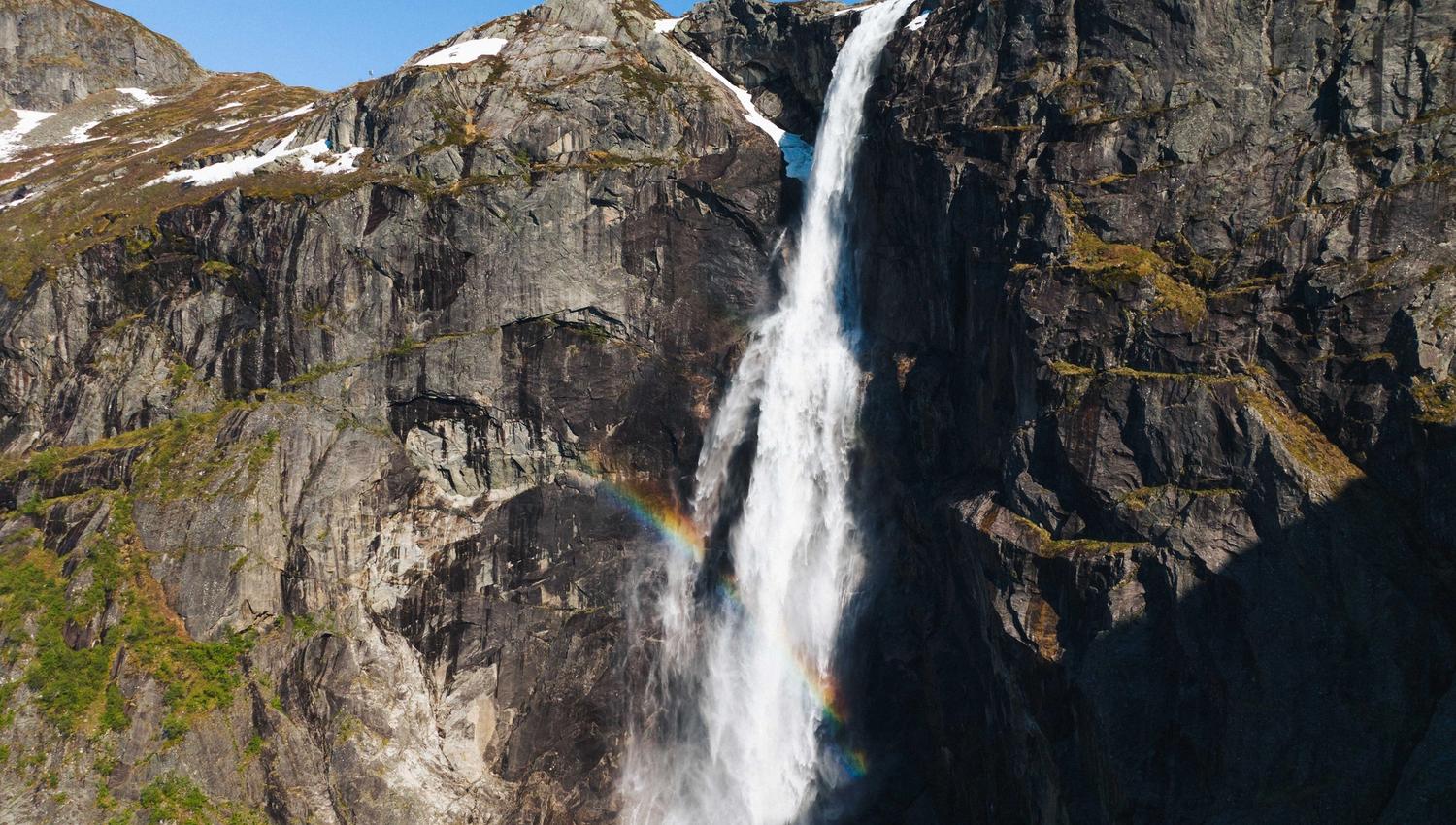 The Skytjefossen waterfall with a rainbow in front.