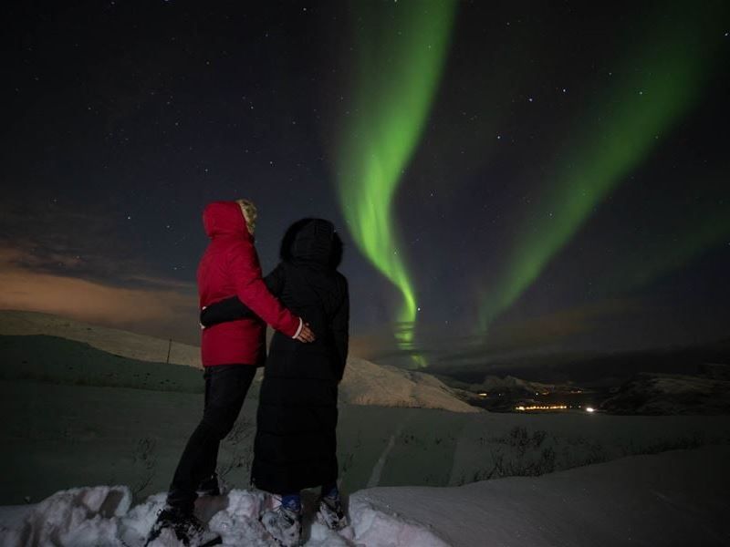 Two people holding each oher looking at the northern lights