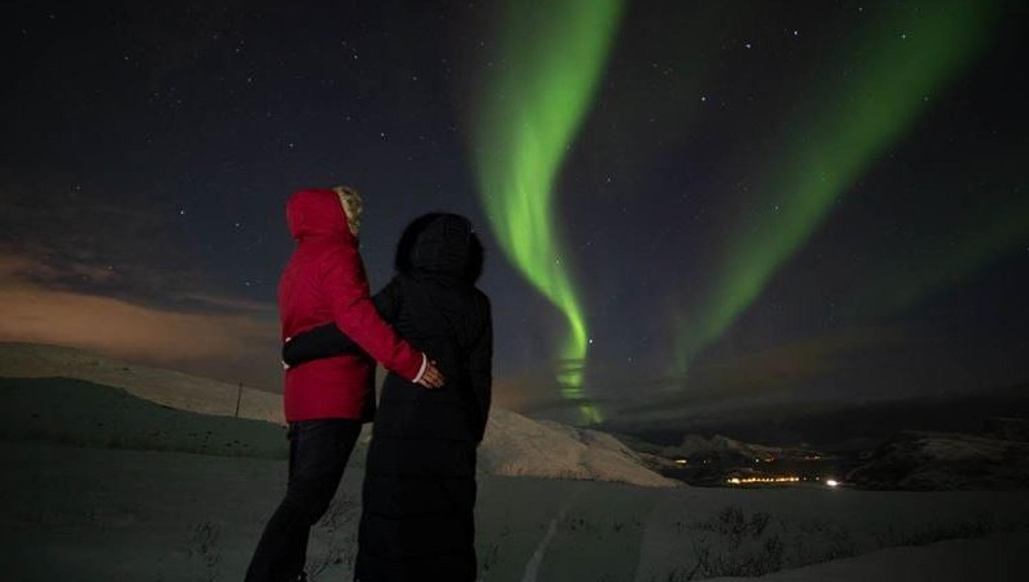 Two people holding each oher looking at the northern lights