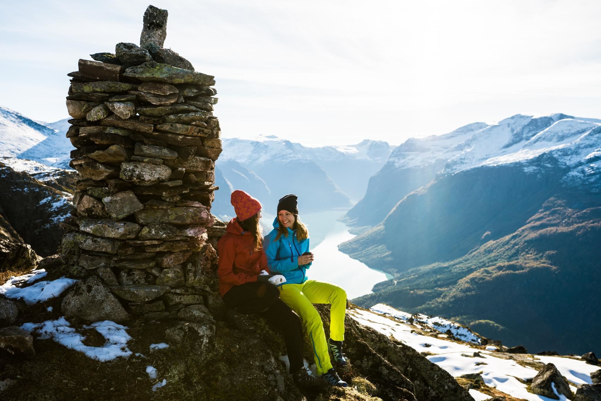 Mountain cairn marking the trail at Hoven, with hikers and dramatic mountain scenery in the background.