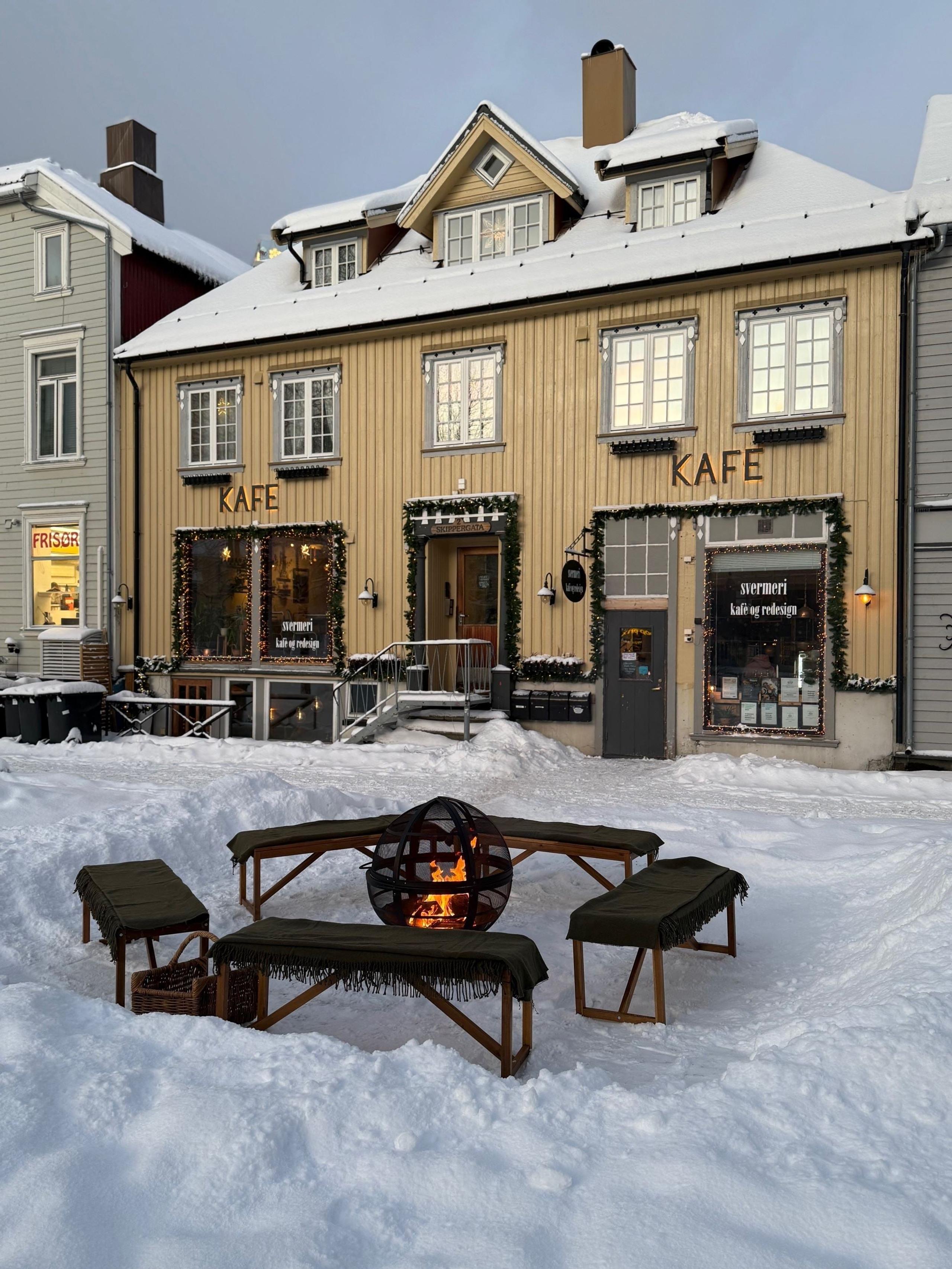 Snødekt utescene med Svermeriet, benker rundt en bålpanne og juledekorasjoner
