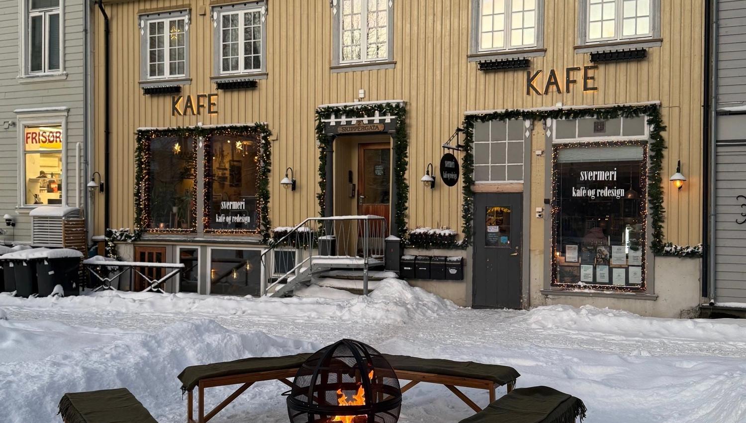 Snødekt utescene med Svermeriet, benker rundt en bålpanne og juledekorasjoner