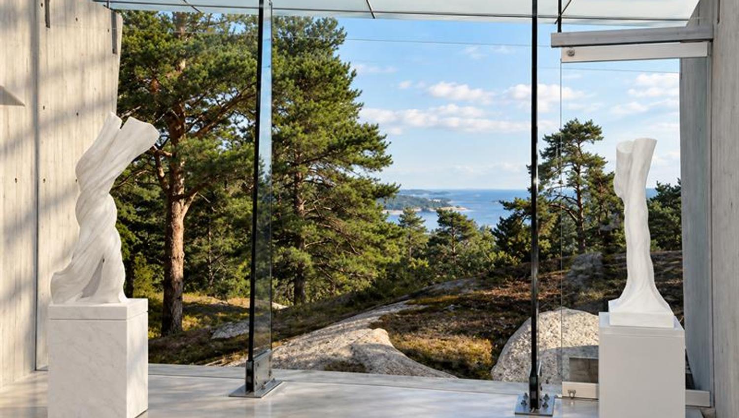 Hvite marmorskulpturer i Midtåsen Skulpturpaviljong med store glassflater og utsikt mot furutrær og Sandefjordsfjorden.