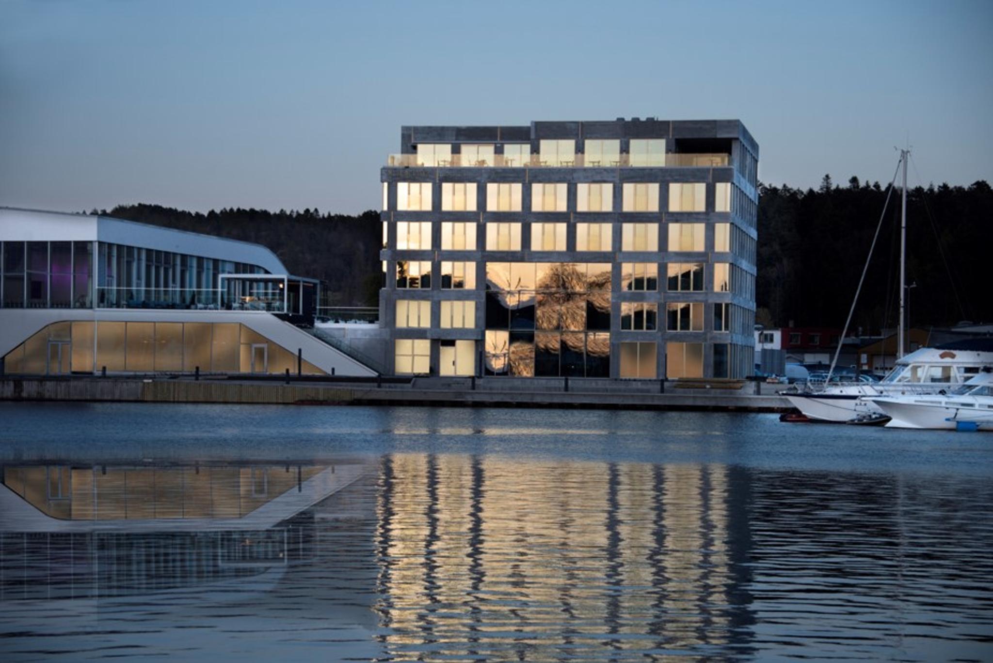 Fasade Mandal Hotel, som speiler seg i Mandalselva ved siden av Buen Kulturhus