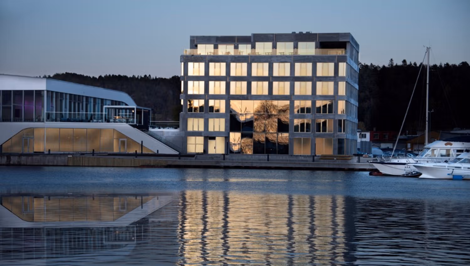 Fasade Mandal Hotel, som speiler seg i Mandalselva ved siden av Buen Kulturhus