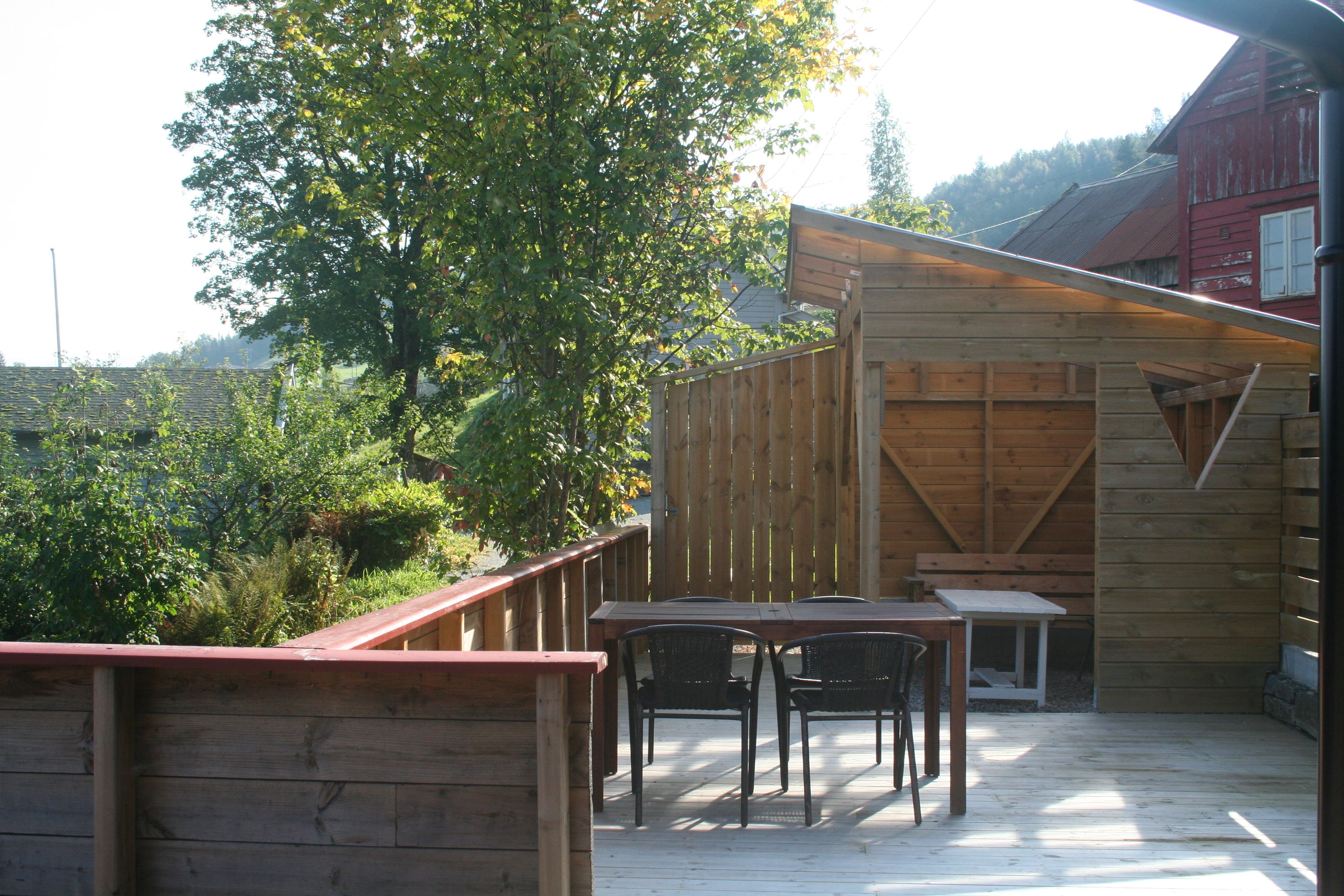 Sunny outdoor patio with seating area and surrounding trees at Vågen Rooms and Cabins.