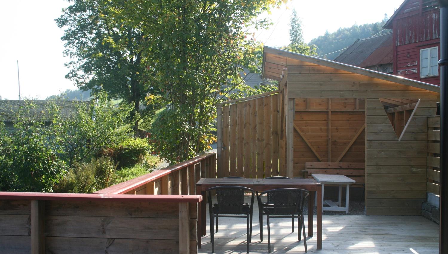 Sunny outdoor patio with seating area and surrounding trees at Vågen Rooms and Cabins.