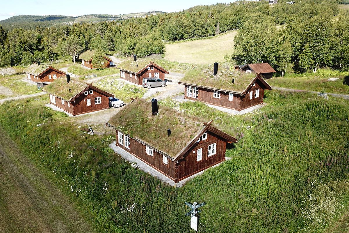 Luftfoto av et hyttetun på seks hytter med gresstak