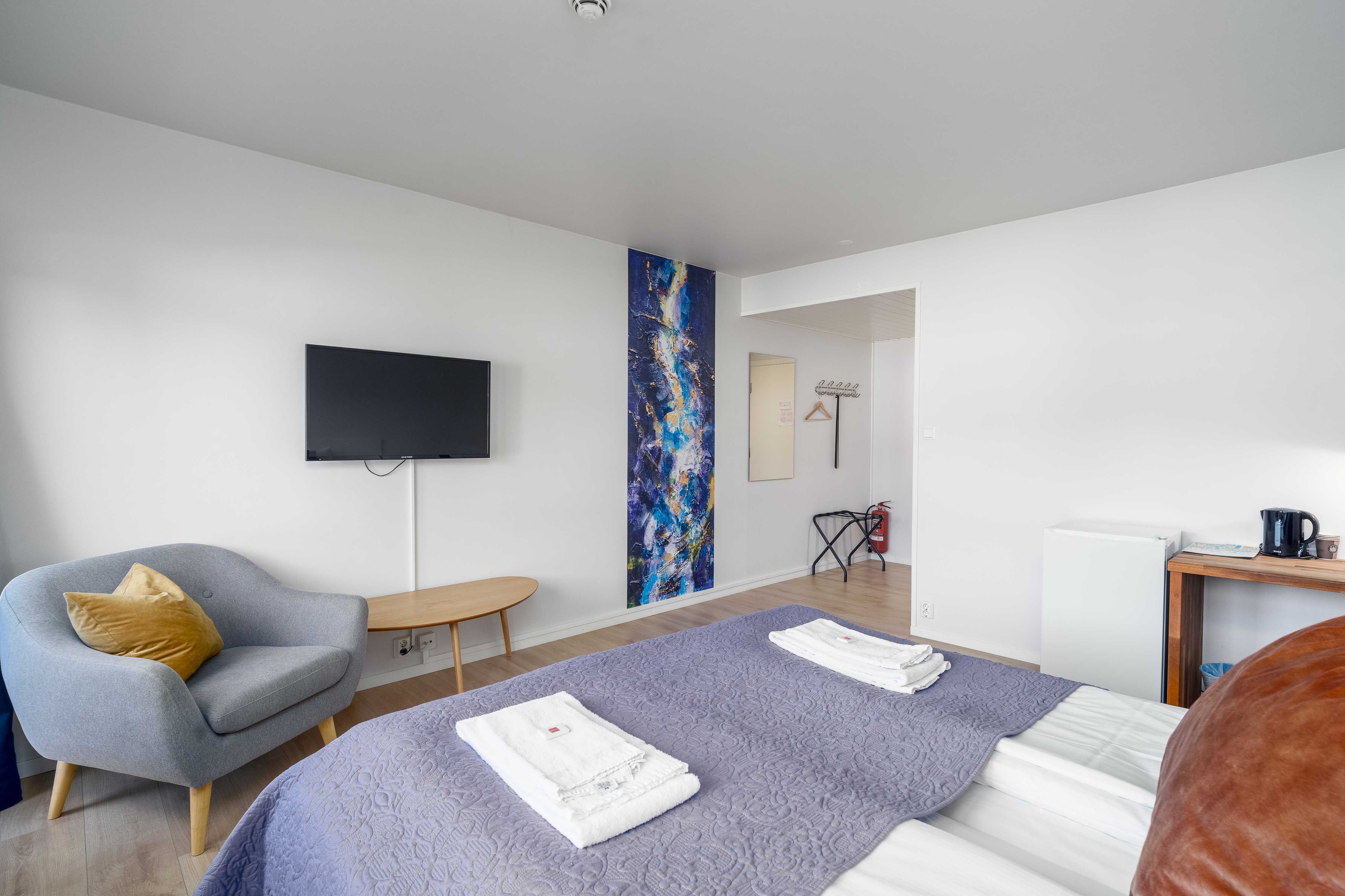 Komfortabelt rom på Husnes Sentrum Hotell med sofa, TV og moderne innreiing.