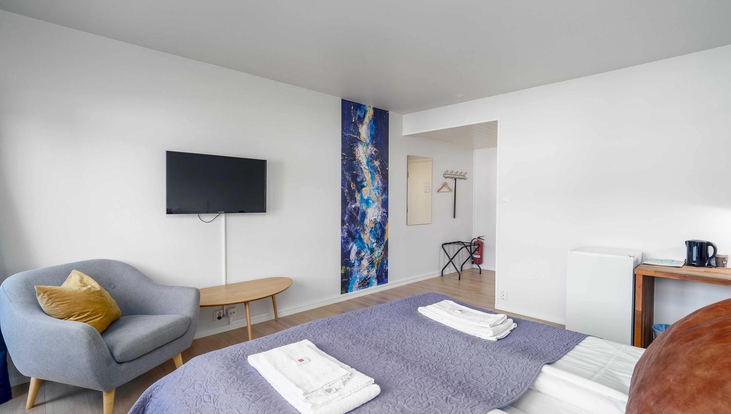 Comfortable room at Husnes Sentrum Hotel with sofa, TV and modern interior design.