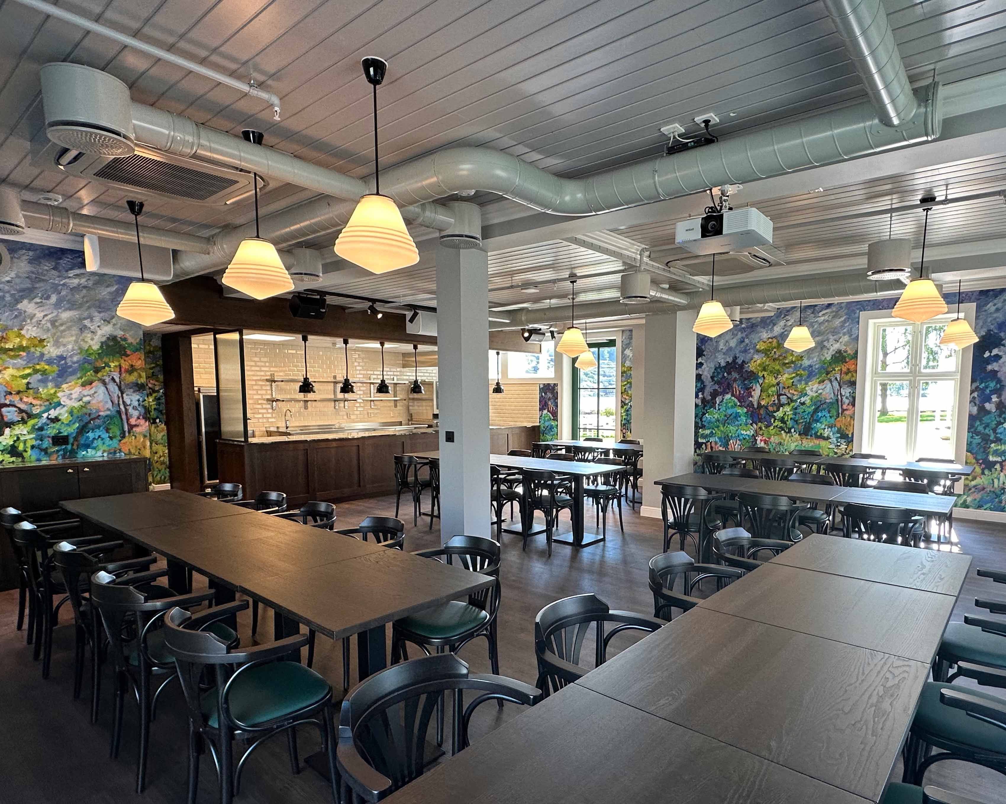 Sjøhuset restaurant & pub features floor-to-ceiling windows framing the stunning fjord views, while pendant lights cast a warm glow over intimate dini