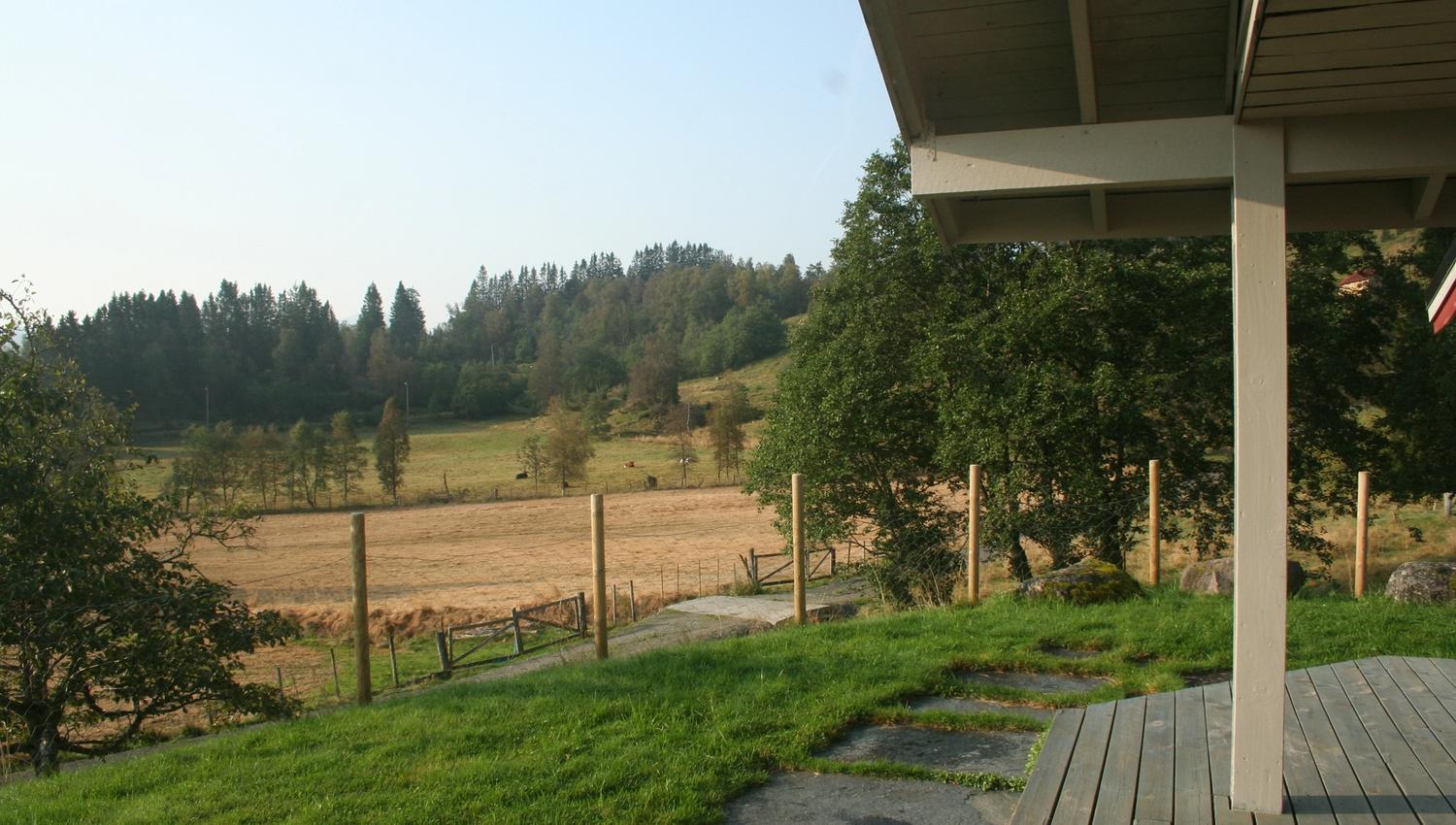 Panoramic view from the cabin over green meadows and forested hills in Hardanger.