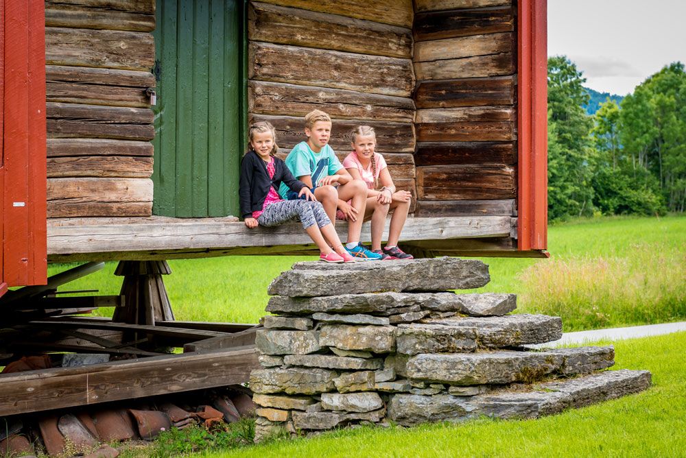 children sit in front of a barn at the Henrik Ibsen museum
