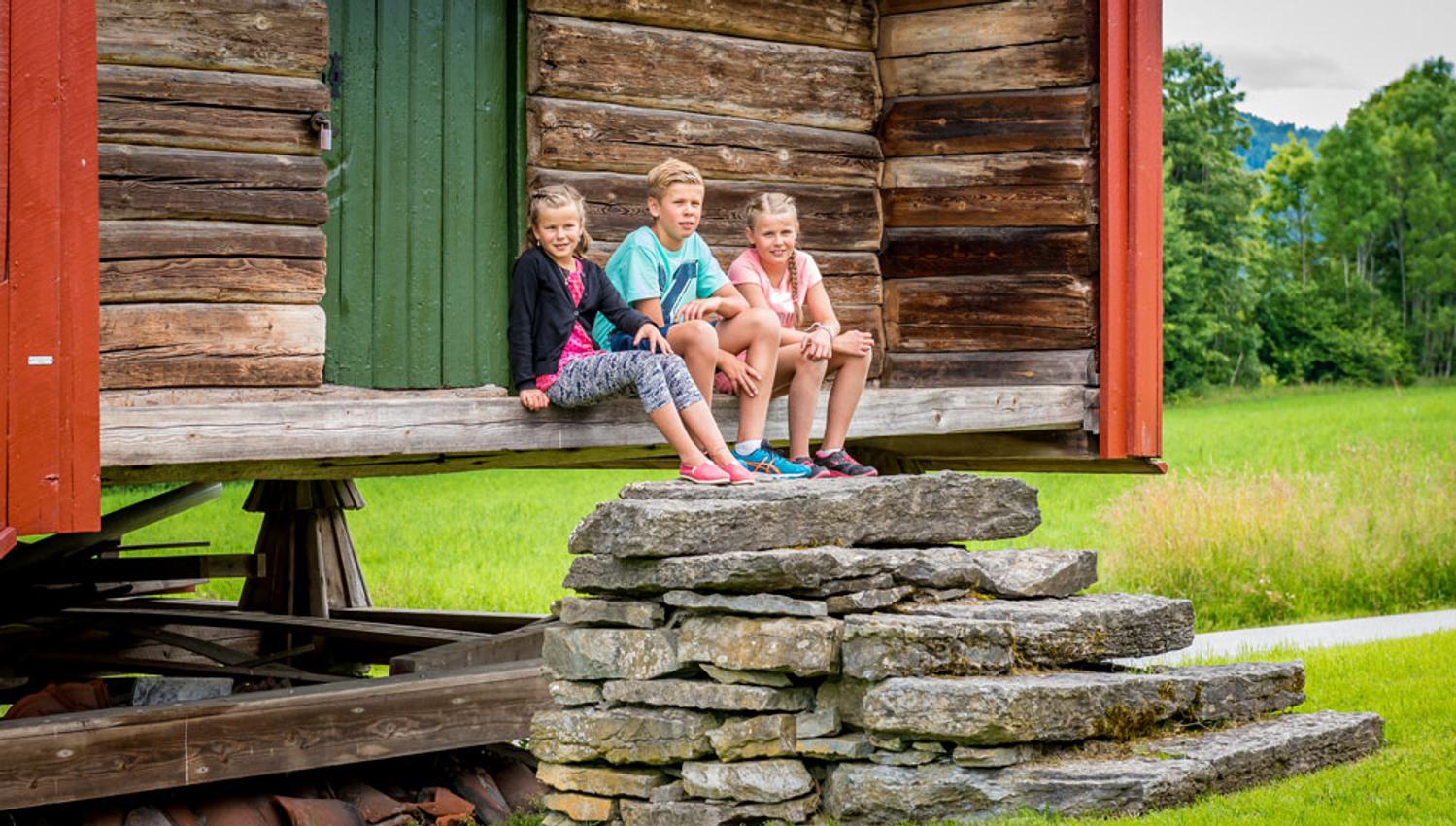 children sit in front of a barn at the Henrik Ibsen museum