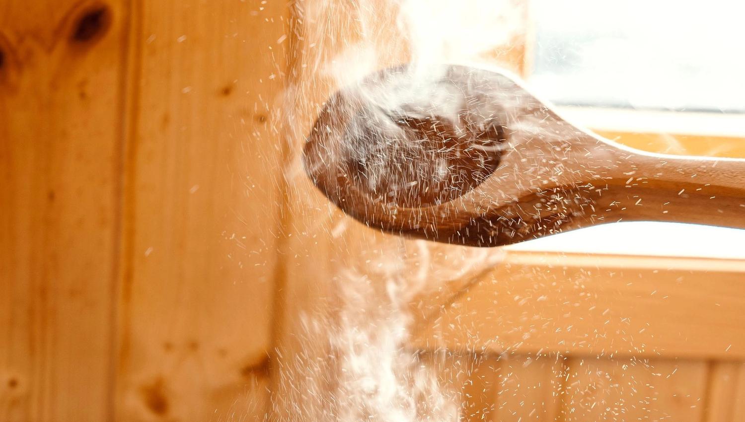 Water splashes onto hot sauna stones from a wooden ladle, sending a cloud of steam in a wood-paneled room at the Seahouse at Hornelen Panorama in Bremanger..