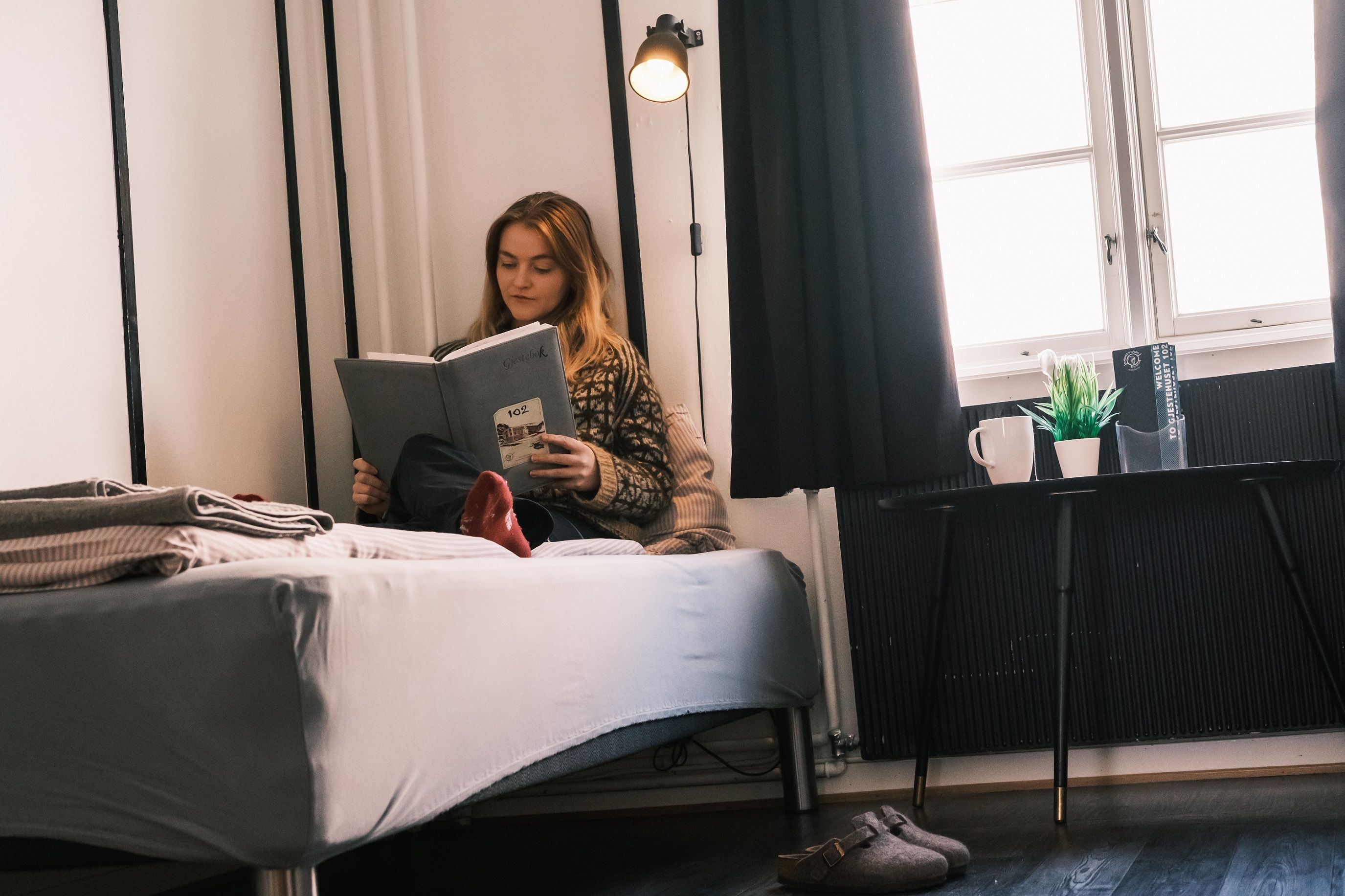 A person sitting in a bed and reading a book.