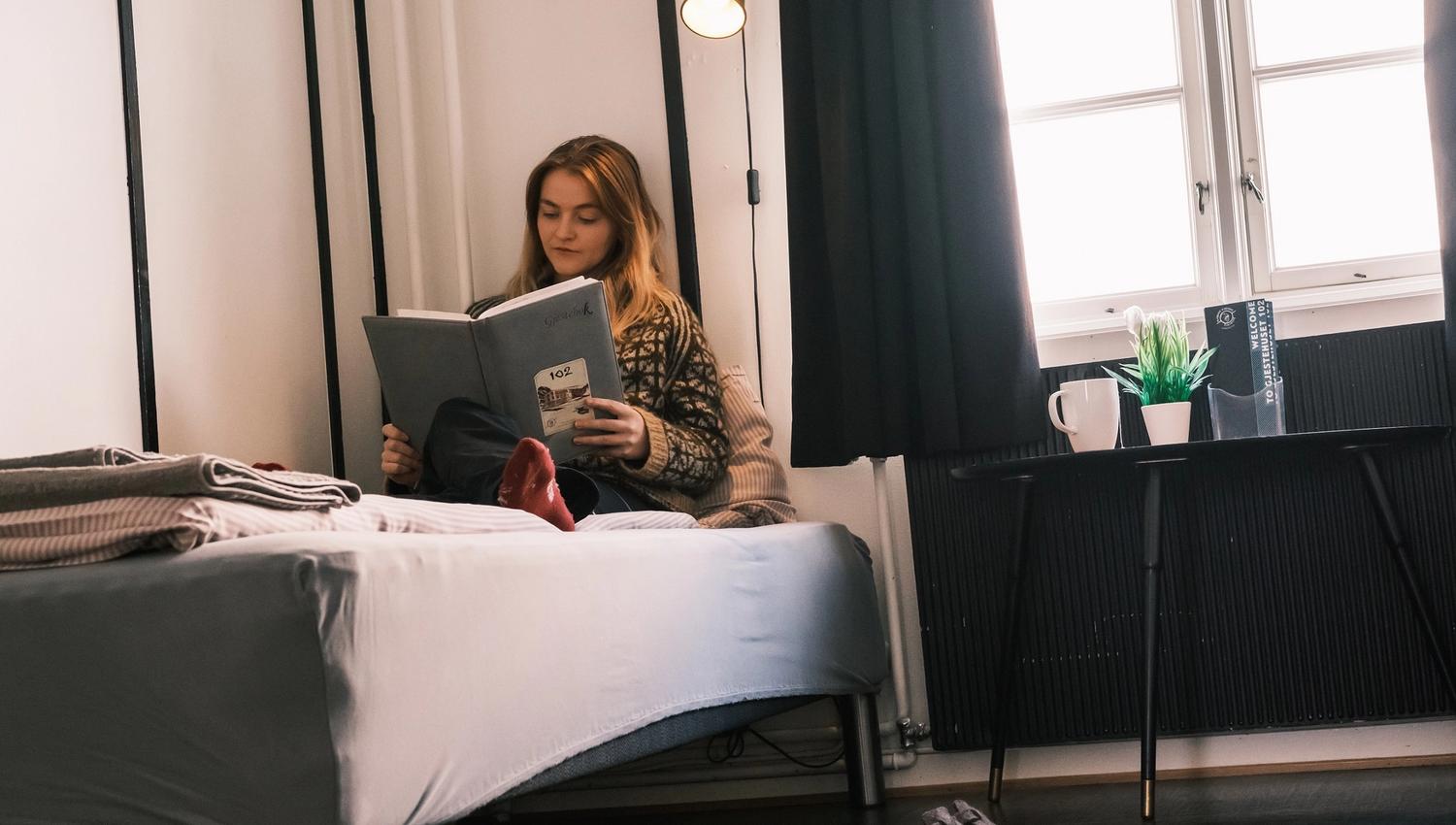 A person sitting in a bed and reading a book.