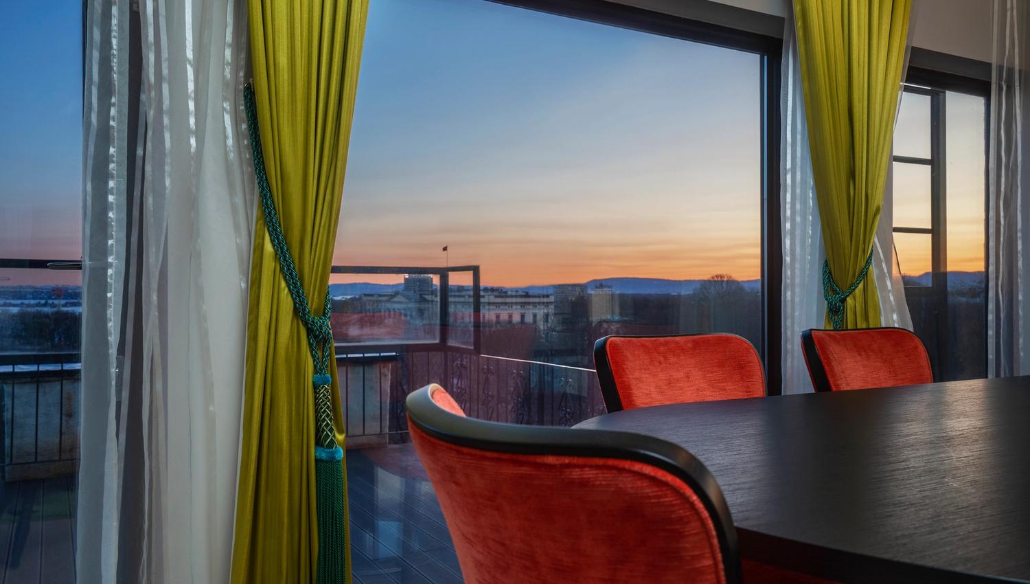 Meeting room with dark table. Red chairs in front of a panorama window. Evening view. Thon Hotel Slottsparken, Oslo. Photo