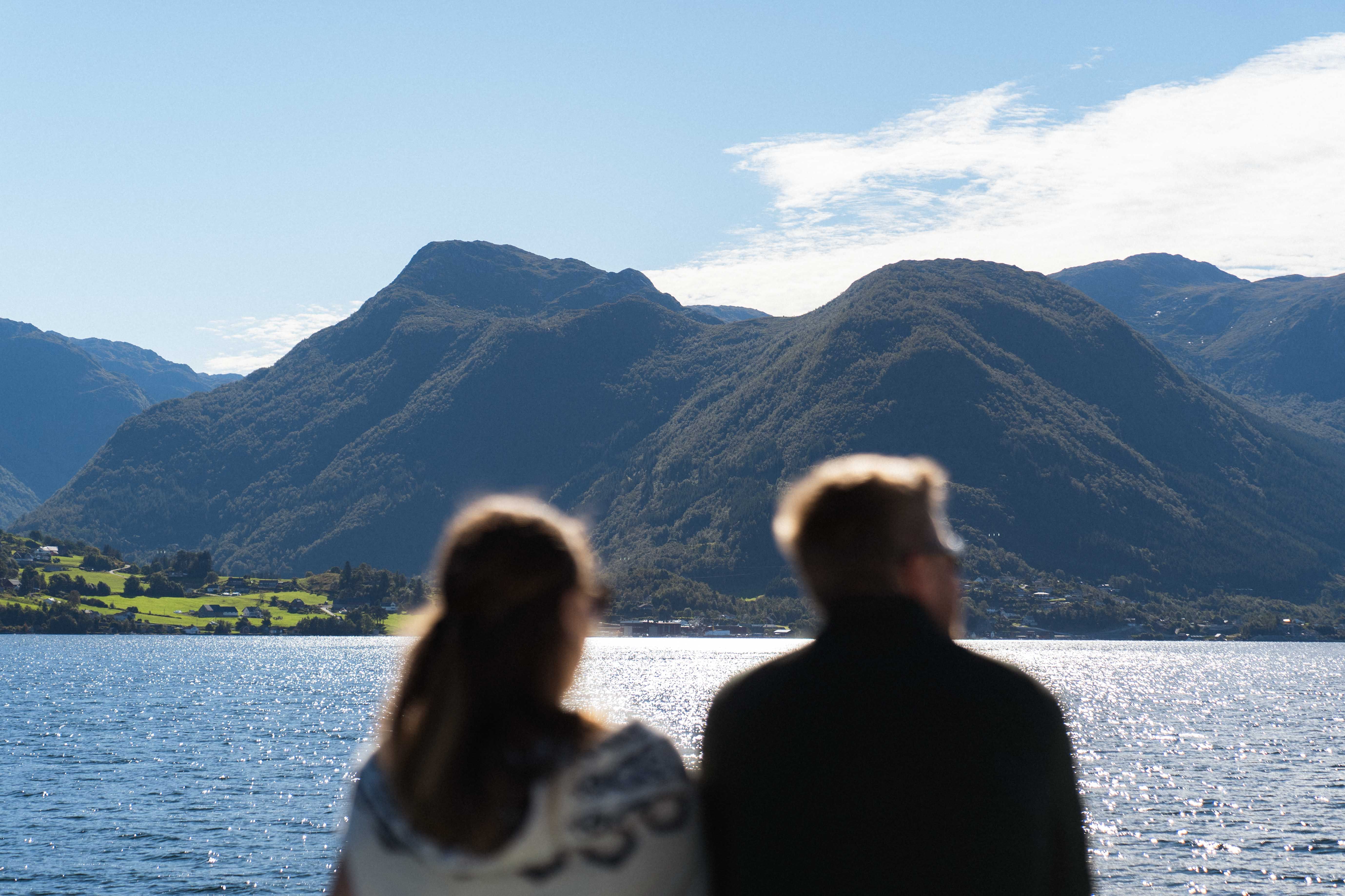 A couple overlooking the Hardangerfjord and mountains from Hardangerfjordekspressen.