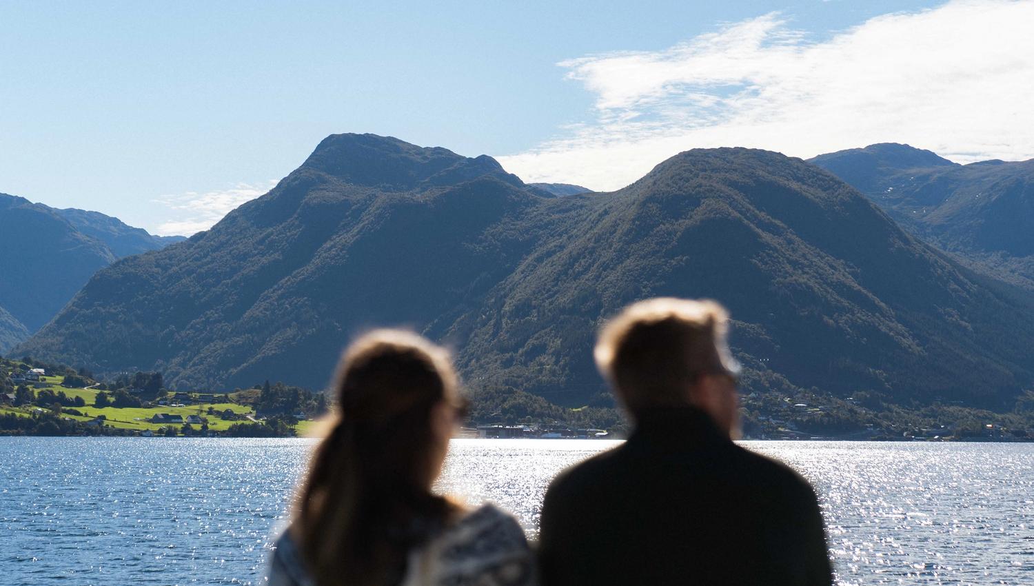 A couple overlooking the Hardangerfjord and mountains from Hardangerfjordekspressen.