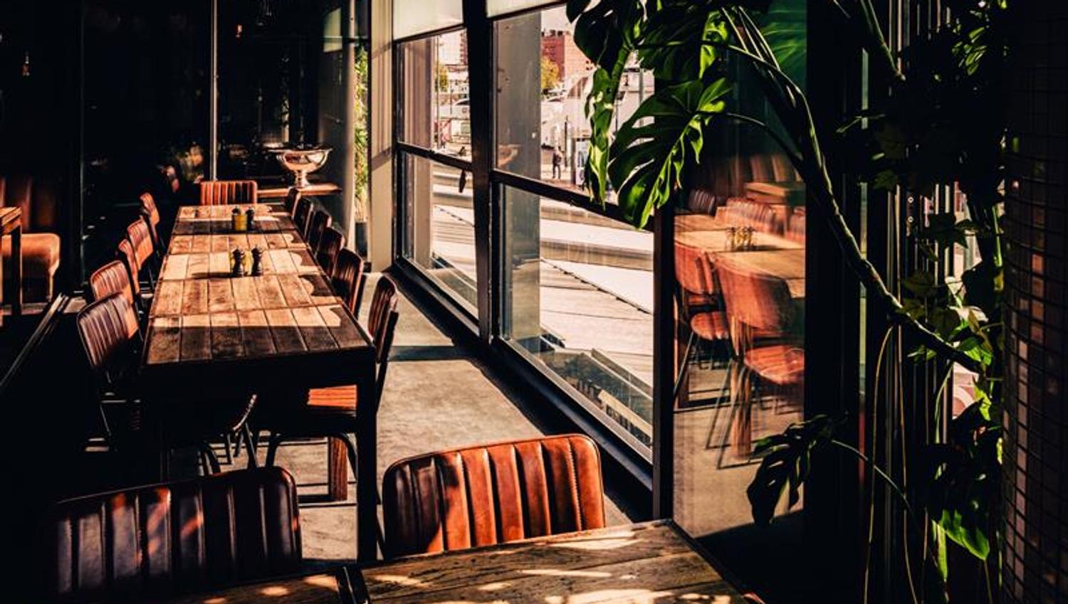 Long tables positioned alongside windows overlooking the street. The space accommodates both small and larger groups.