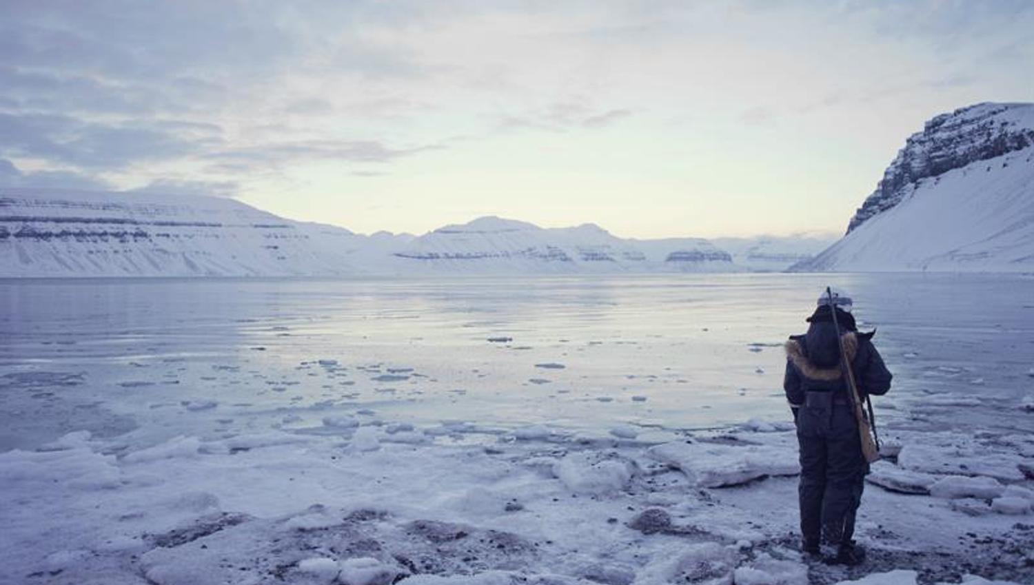 Guide stående ved isen med rifle