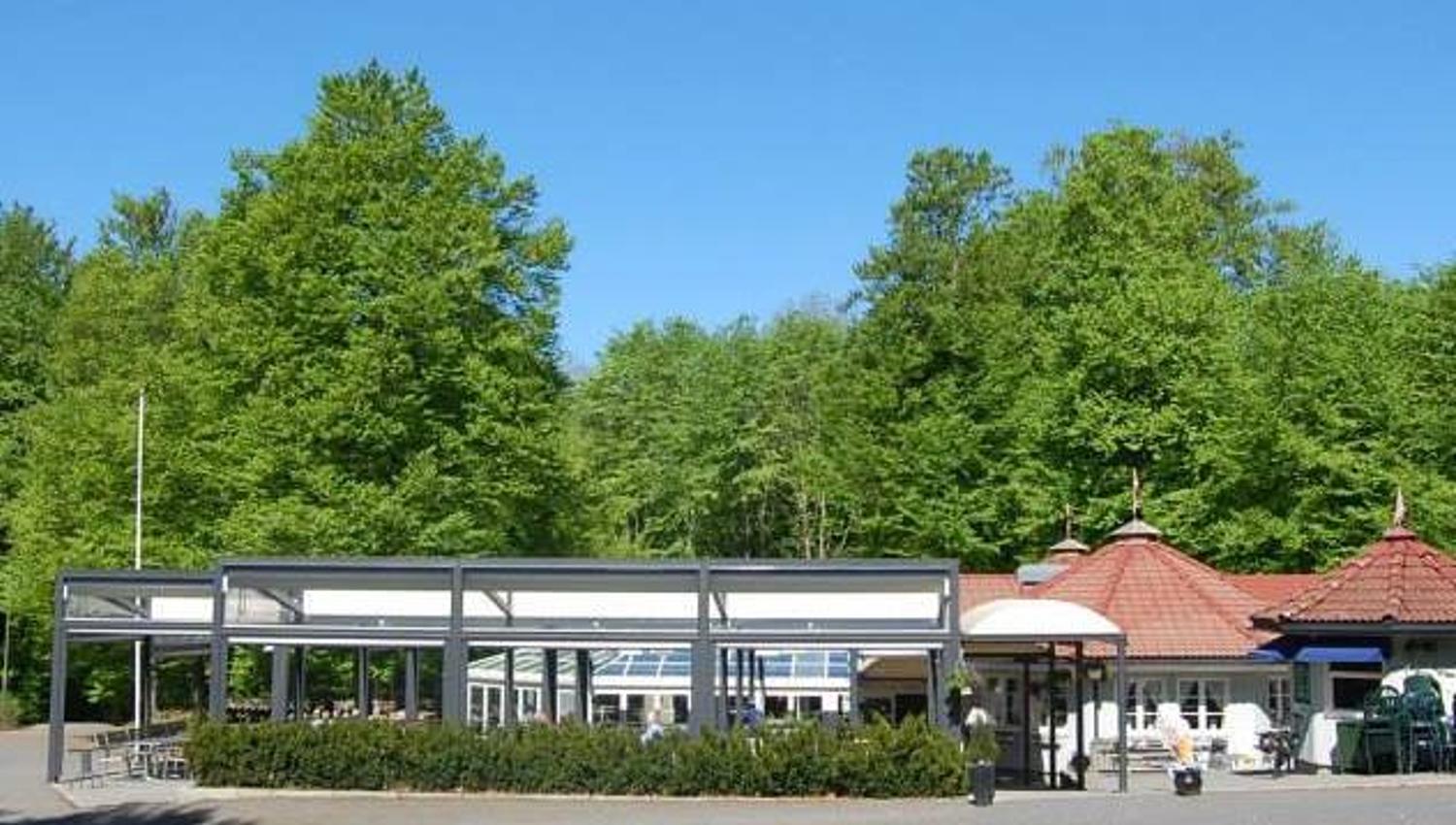 The restaurant in the foreground with a green beech forest behind.