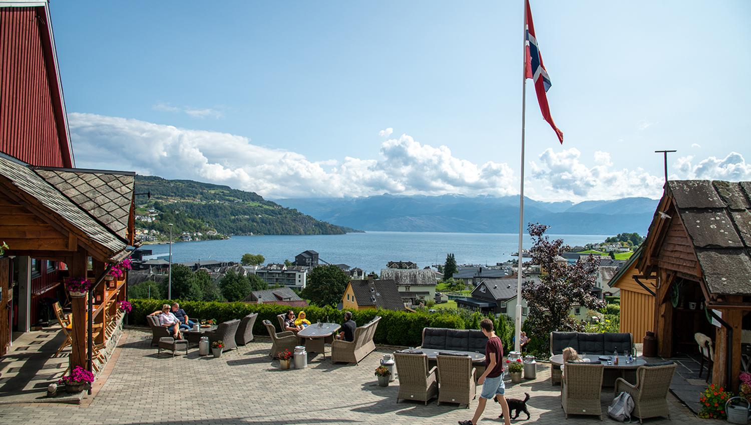 Outdoor dining at Eldhuset Farm Restaurant with a sunny view over the Hardangerfjord.