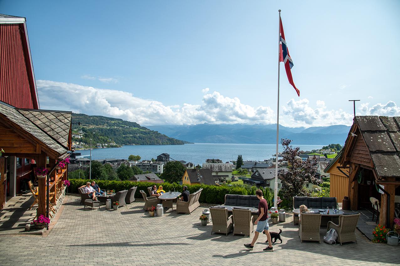 Outdoor dining at Eldhuset Farm Restaurant with a sunny view over the Hardangerfjord.