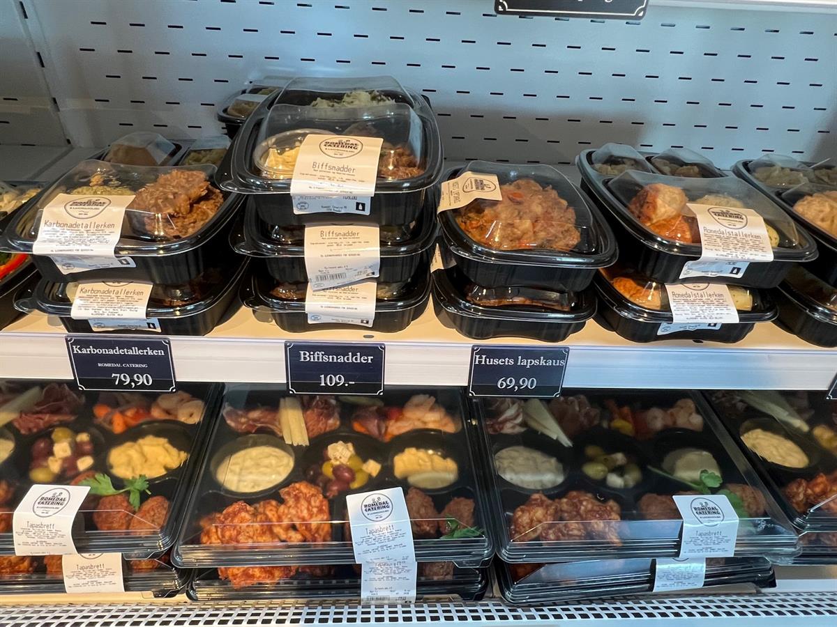 Pre-packaged meals stacked in a refrigerated display in a store.