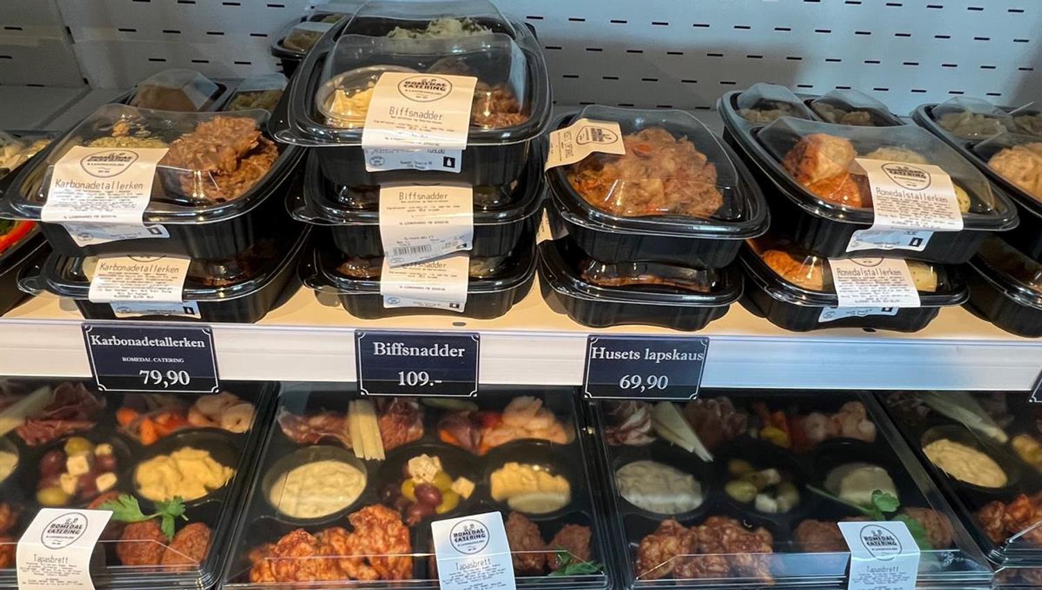 Pre-packaged meals stacked in a refrigerated display in a store.