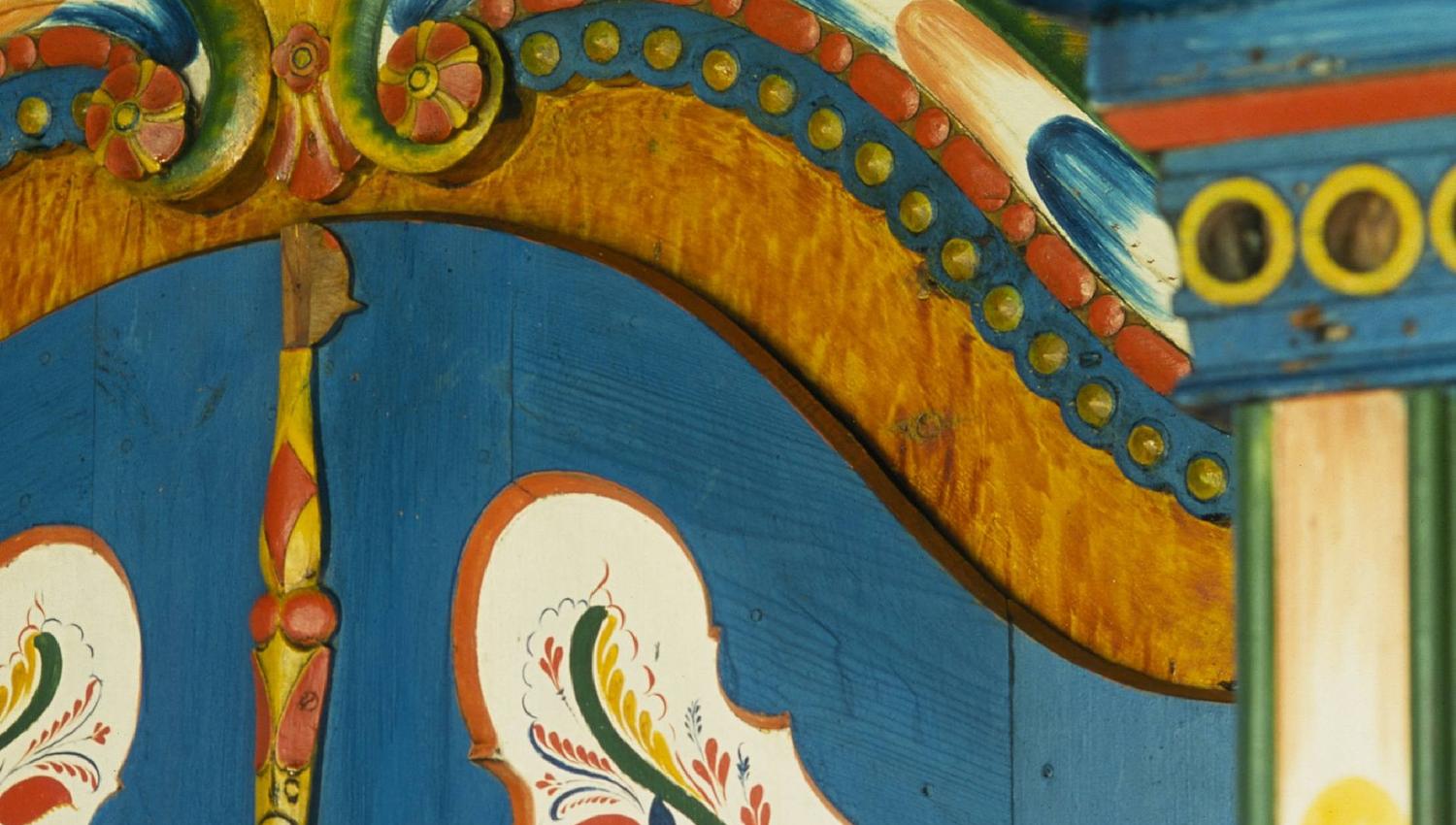 Blue cabinet with rosemaling and “Mjaaland” in cursive script