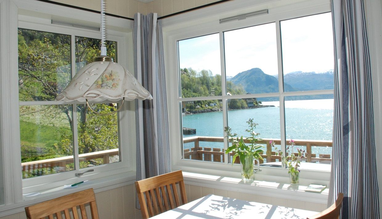 Dining area with a view of the Hardangerfjord – bright interiors and a peaceful seaside atmosphere.