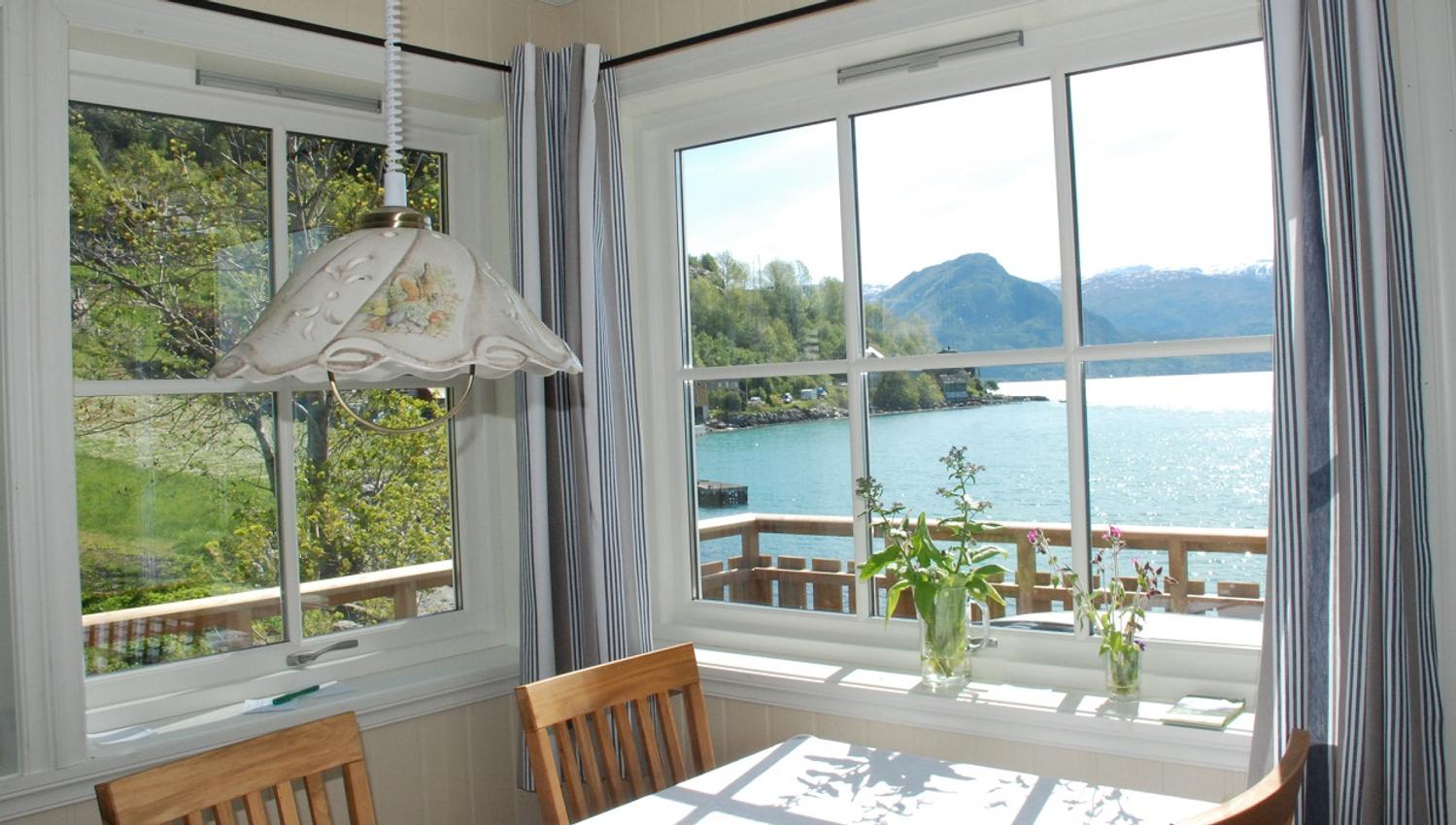 Dining area with a view of the Hardangerfjord – bright interiors and a peaceful seaside atmosphere.