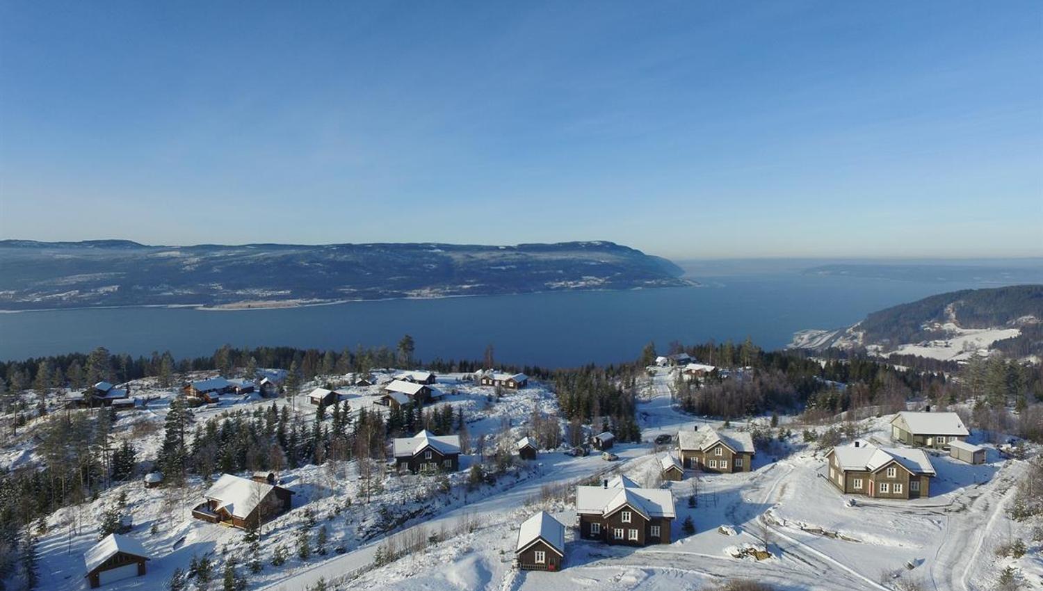 Winter landscape with cabins overlooking a lake and mountains.