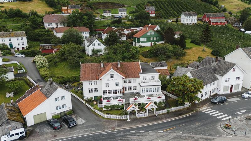 Aerial view of Utne Hotel among white wooden houses and fruit orchards in the village of Utne, Hardanger.