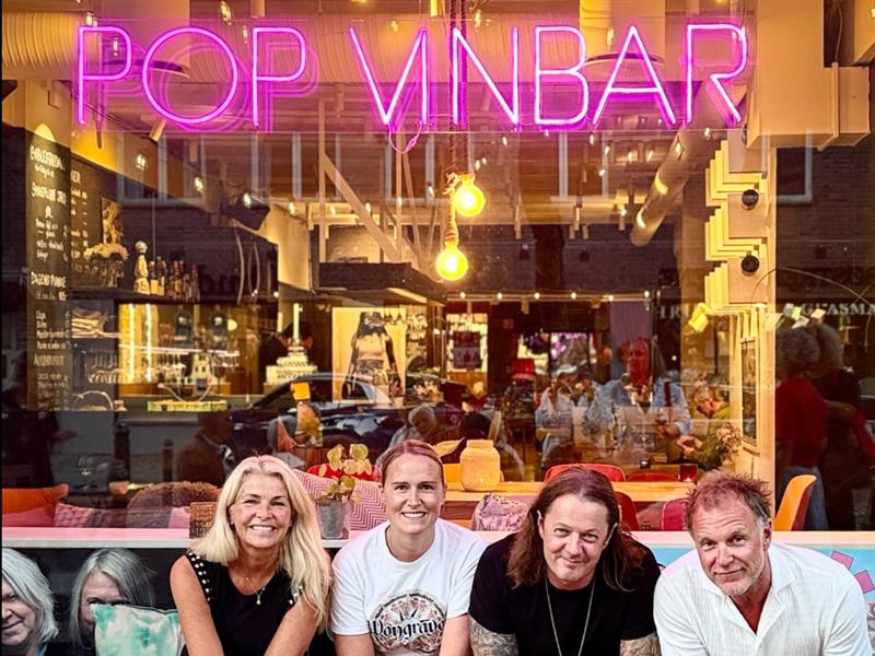 Fire personer på en benk utenfor POP Vinbar