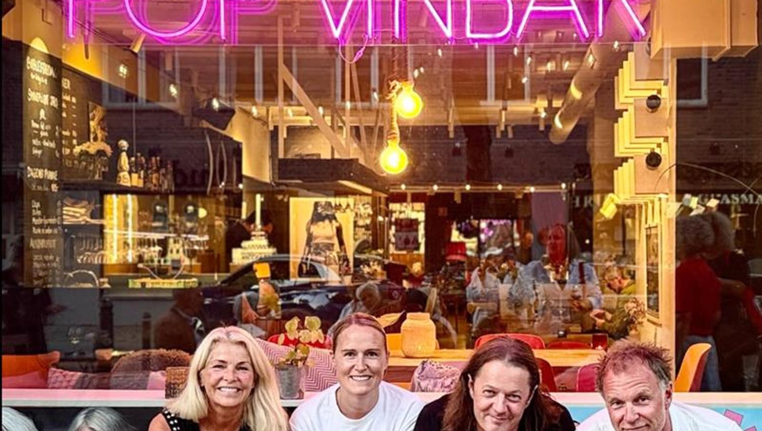 Fire personer på en benk utenfor POP Vinbar