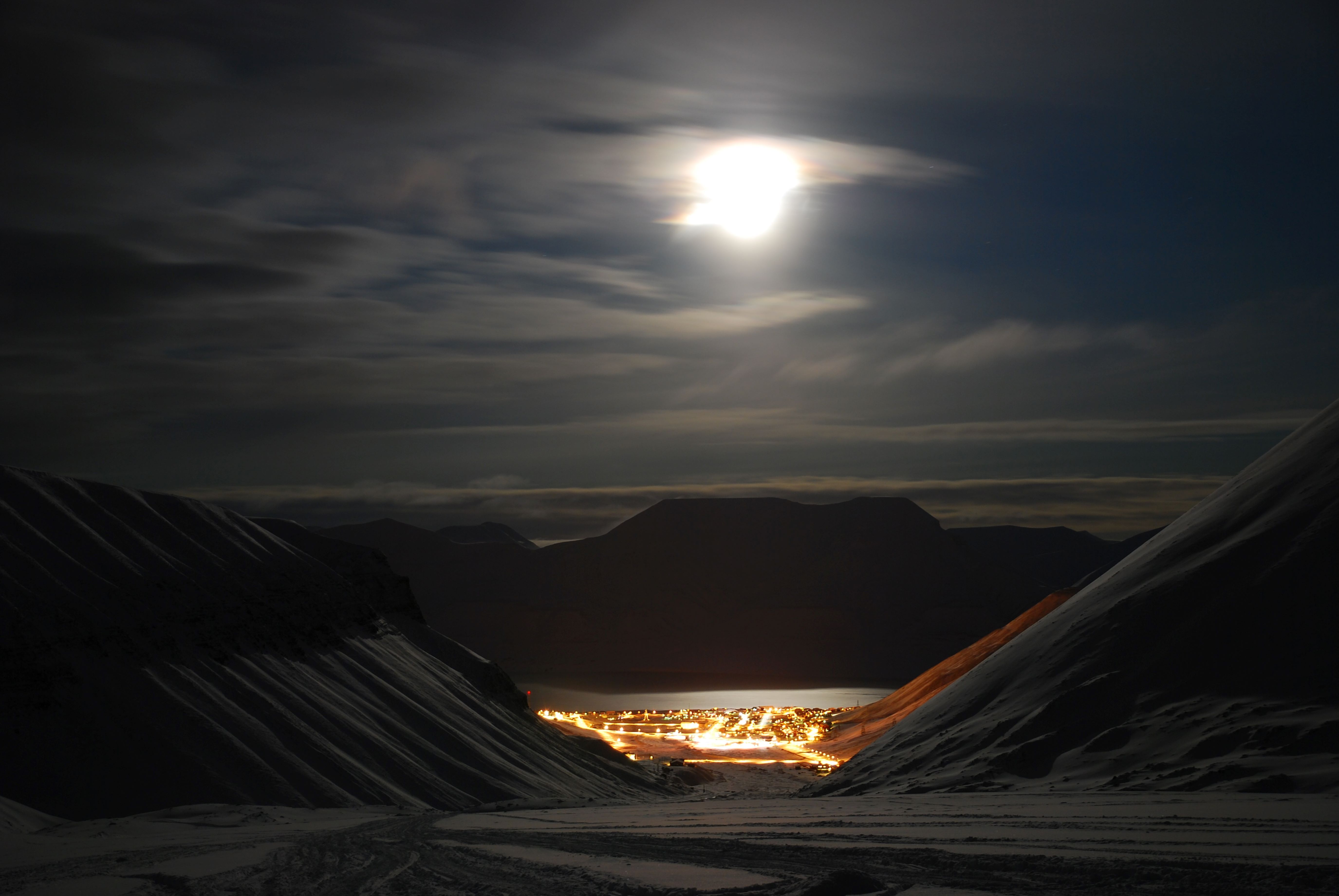 Longyearbyen i enden av dalen. Måneskinnet lyser opp fjellene rundt.