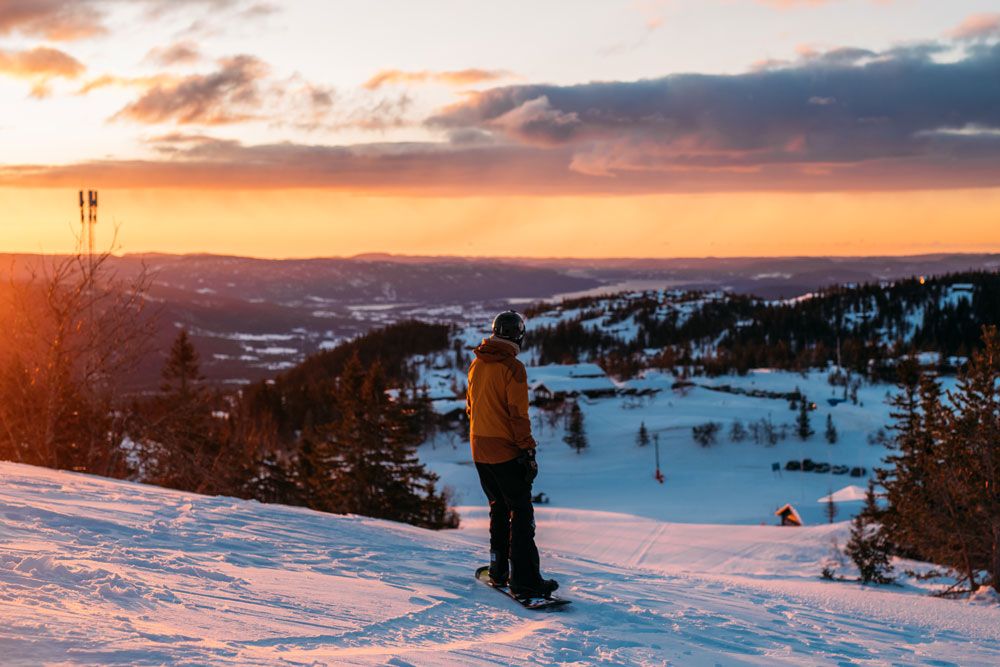 boy snowboarding at the top of the alpine hill at Lifjell ski center at sunset