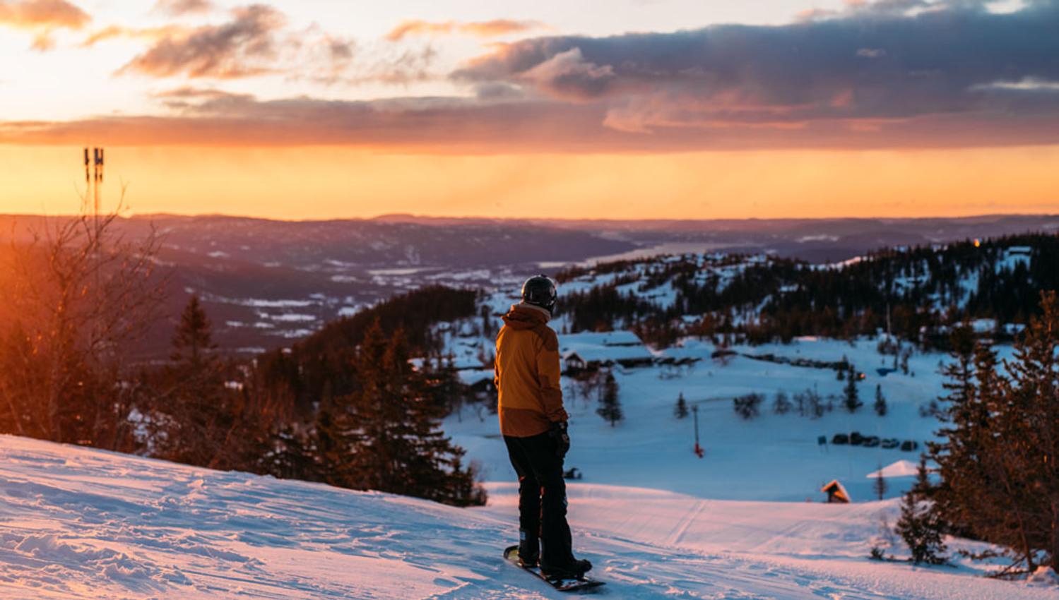 boy snowboarding at the top of the alpine hill at Lifjell ski center at sunset