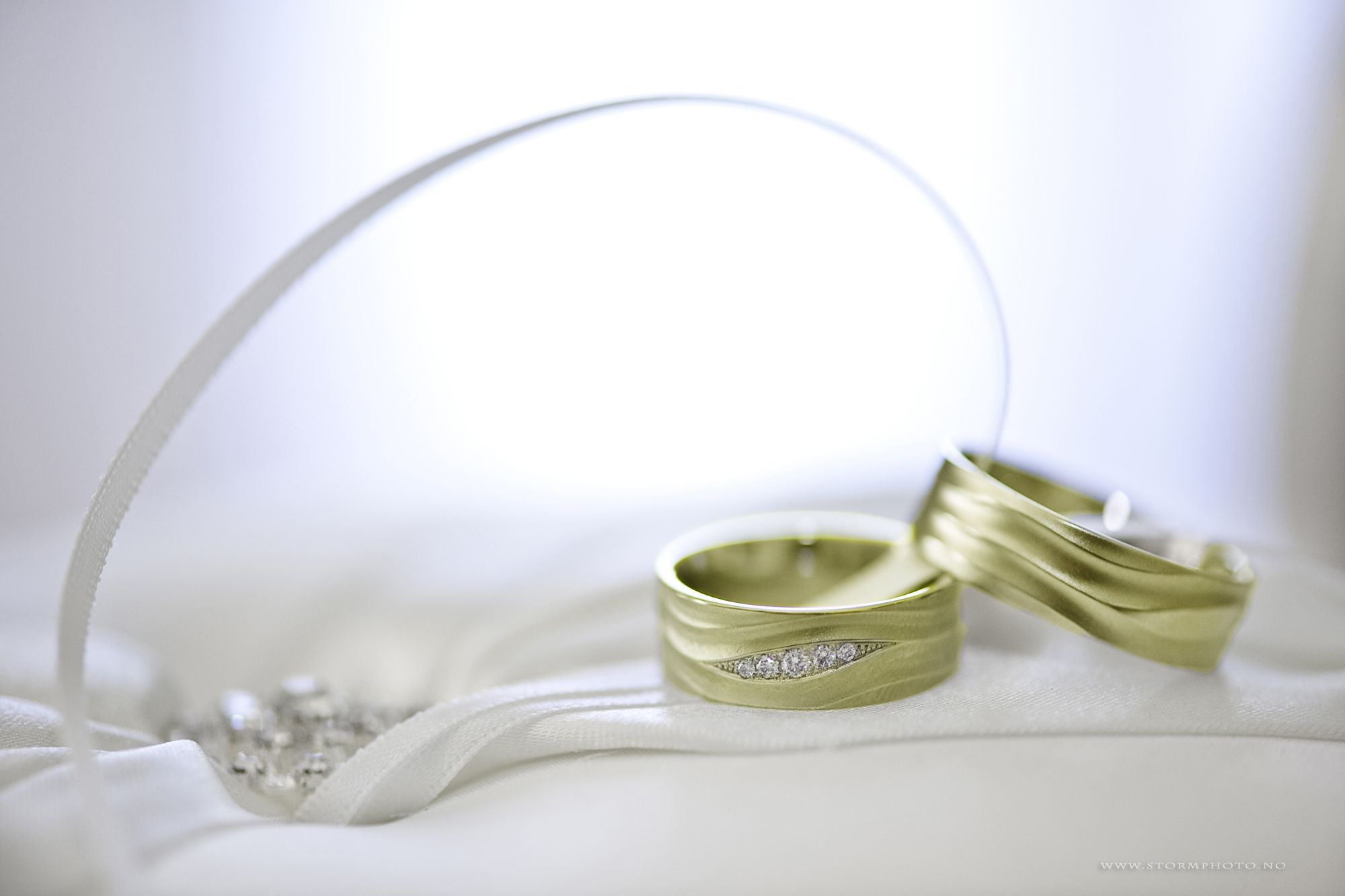 Two wedding rings on white satin with a ribbon