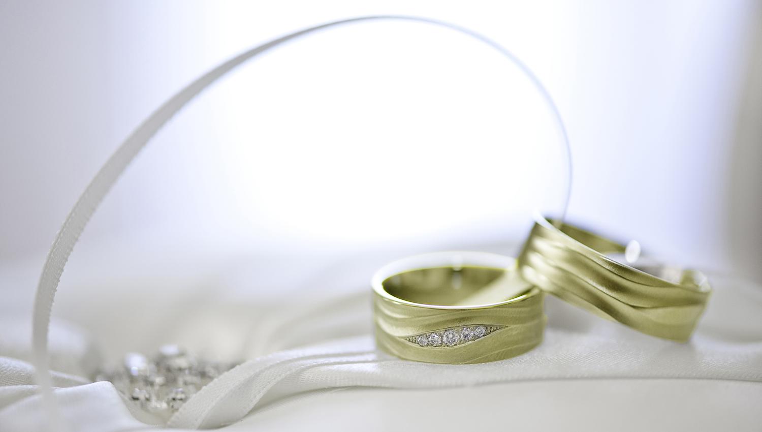 Two wedding rings on white satin with a ribbon