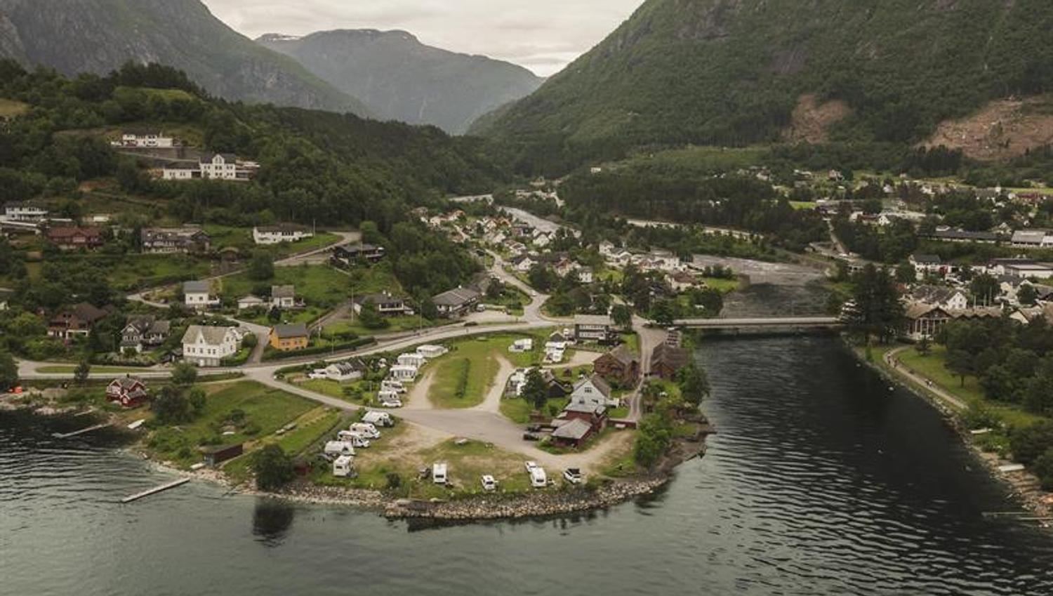 A drone photo of the camping place with the village and mountains in the background.