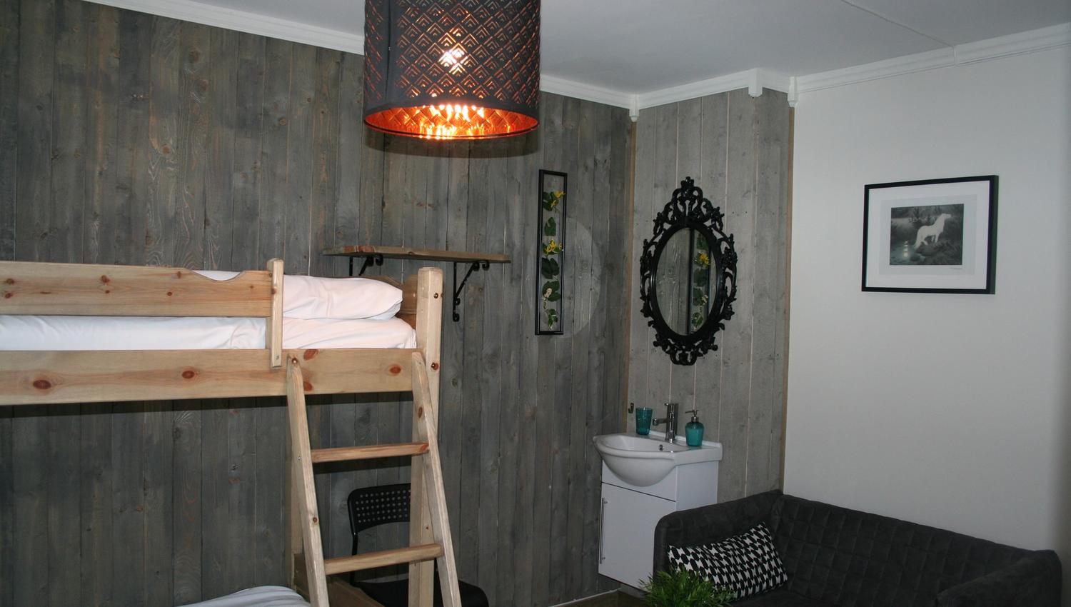 Family room at Kvamseter Lodge featuring bunk beds, a small sofa area, and modern decor.